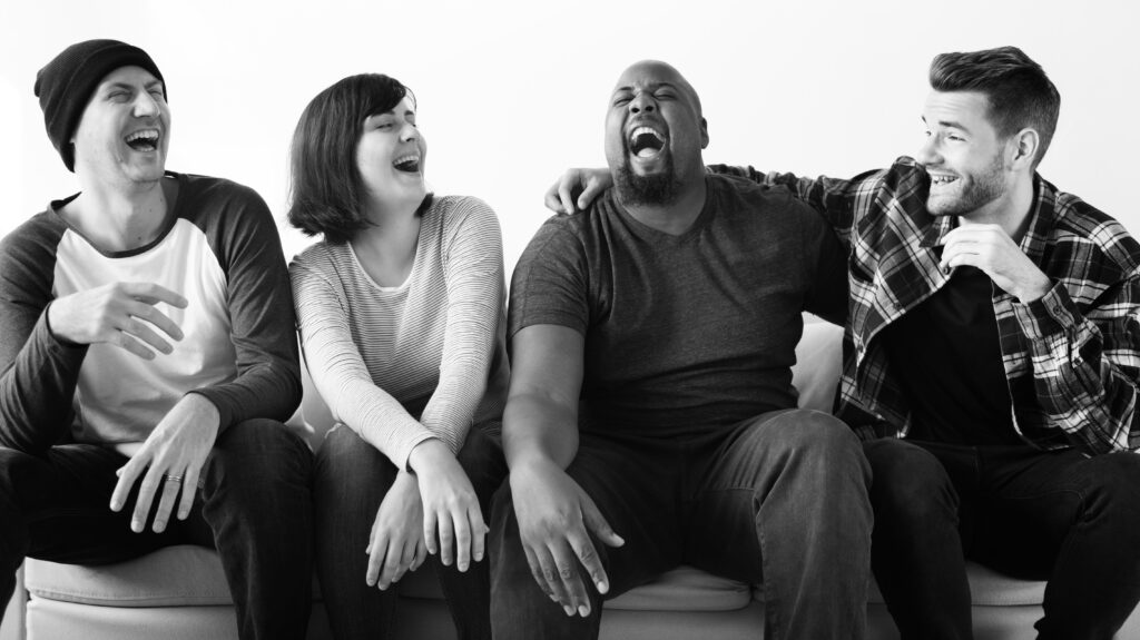 Groupe de collègues riant ensemble lors d'un atelier de yoga du rire, favorisant le bien-être au travail.